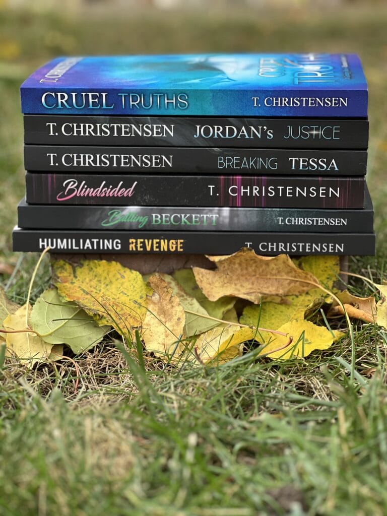 All six of T. Christensen's books are stacked on top of each other. Only the spines displaying the titles are visible. The stack is on grass with colored fall leaves in front of the stack.